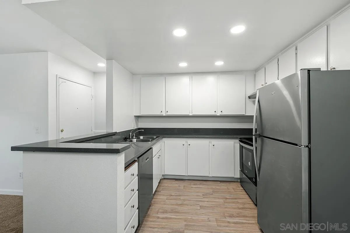 6006 Rancho Mission Road San Diego, CA 92108 - Photo 16 of 32 a kitchen with a sink a refrigerator and a stove top oven with wooden floor