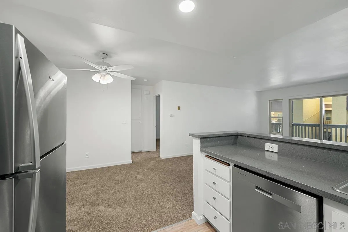 6006 Rancho Mission Road San Diego, CA 92108 - Photo 17 of 32 an open kitchen with granite countertop a sink and dishwasher with wooden floor