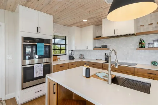 a kitchen with stainless steel appliances granite countertop a sink a stove and a wooden floors