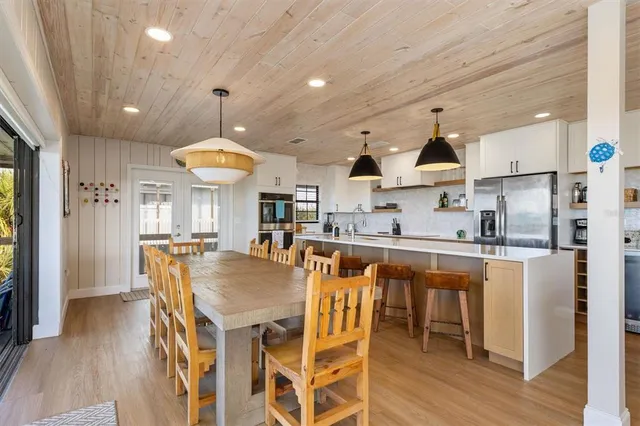 a kitchen with stainless steel appliances granite countertop a refrigerator a stove a sink dishwasher and white cabinets with wooden floor