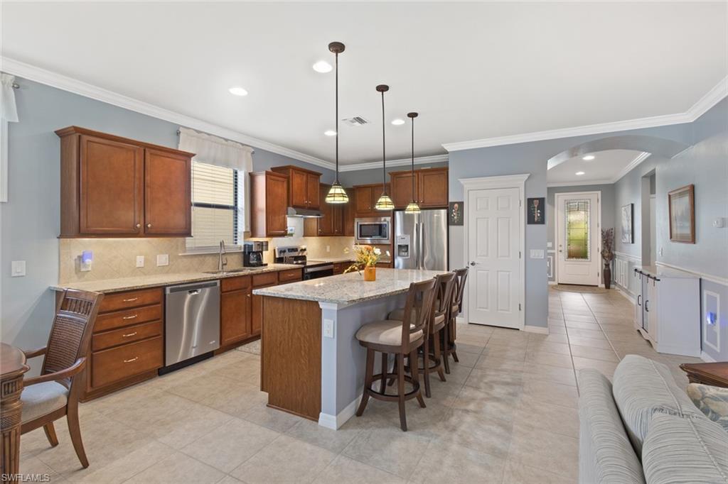 6085 Triumph Lane Ave Maria, FL 34142 - Photo 2 of 42 a kitchen with stainless steel appliances granite countertop a table chairs sink refrigerator and cabinets