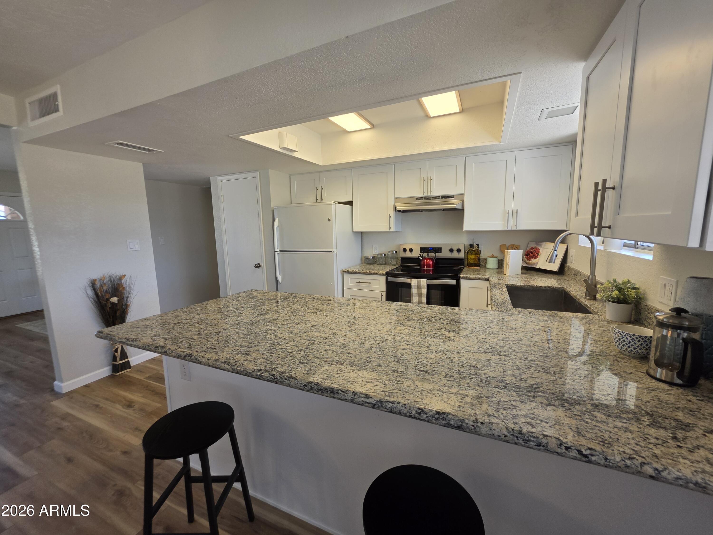 46 East McLellan Road Mesa, AZ 85201 - Photo 6 of 18 a kitchen with stainless steel appliances granite countertop a stove top oven a sink a refrigerator and white cabinets