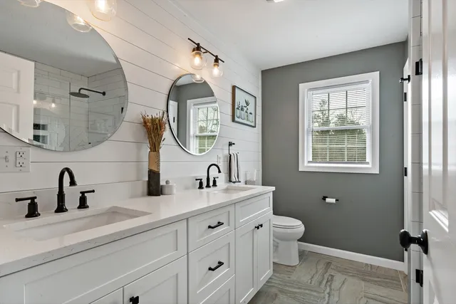 a bathroom with a double vanity sink mirror and toilet