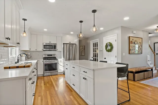 a large white kitchen with lots of counter space a sink appliances and cabinets