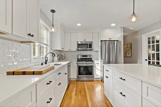 a large kitchen with stainless steel appliances granite countertop a sink a stove a refrigerator and cabinets