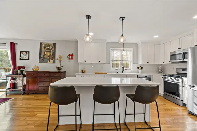 a living room with stainless steel appliances kitchen island granite countertop a dining table chairs and white cabinets