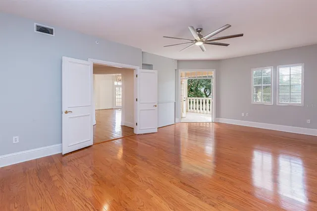 a view of an empty room with wooden floor and a window