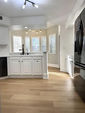 a large white kitchen with wooden floor and a sink
