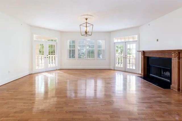 an empty room with wooden floor fireplace and windows