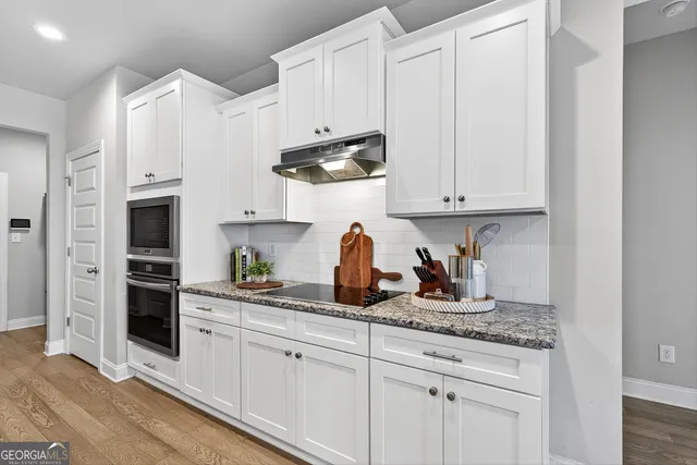 a kitchen with stainless steel appliances granite countertop white cabinets and a sink