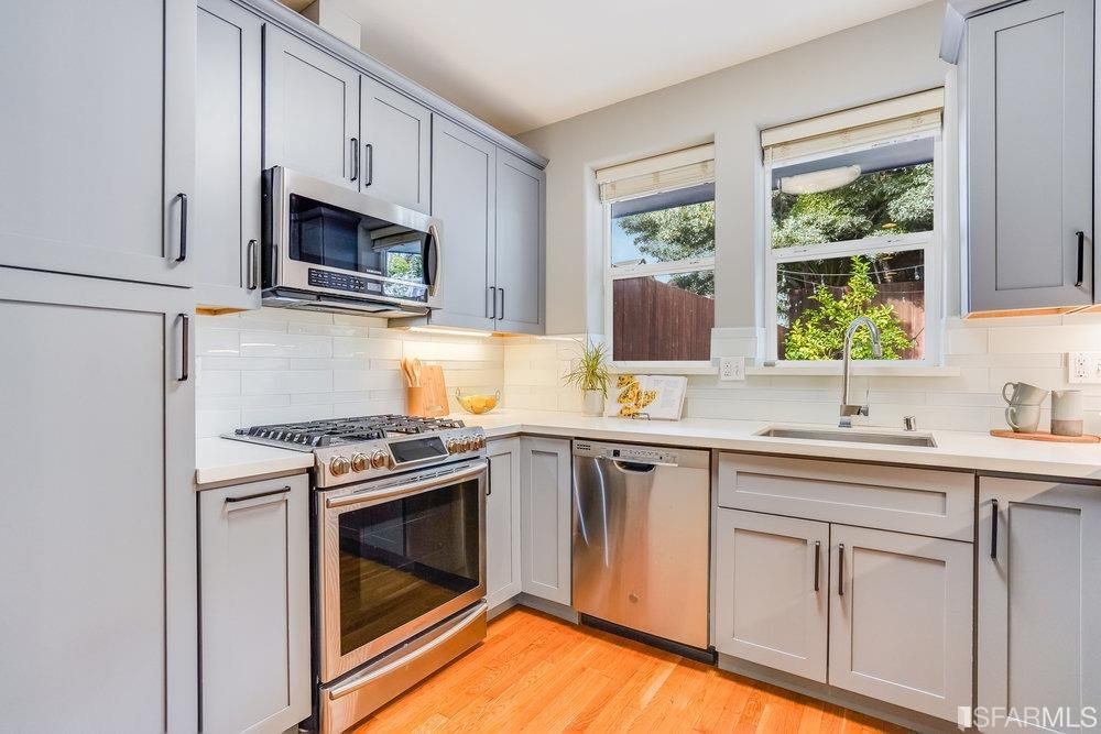 a kitchen with white cabinets appliances and window