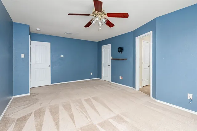 a view of a bedroom with a chandelier fan and windows