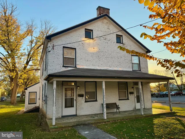 a view of a white house with a large windows and a yard and a large tree