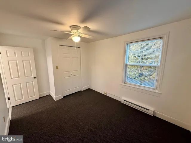 an empty room with windows and fan