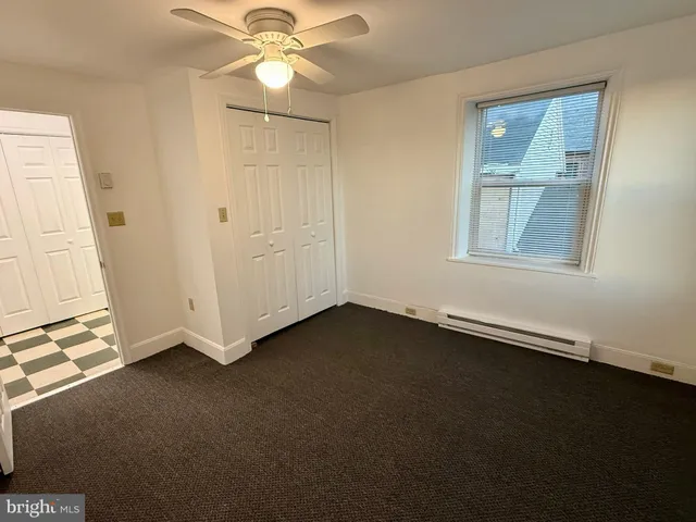 an empty room with a fan & a window