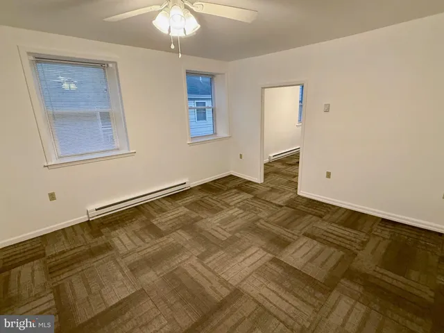 a view of empty room with window and ceiling fan