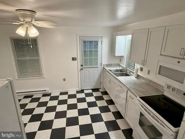 a kitchen with a checkered floor and white cabinets