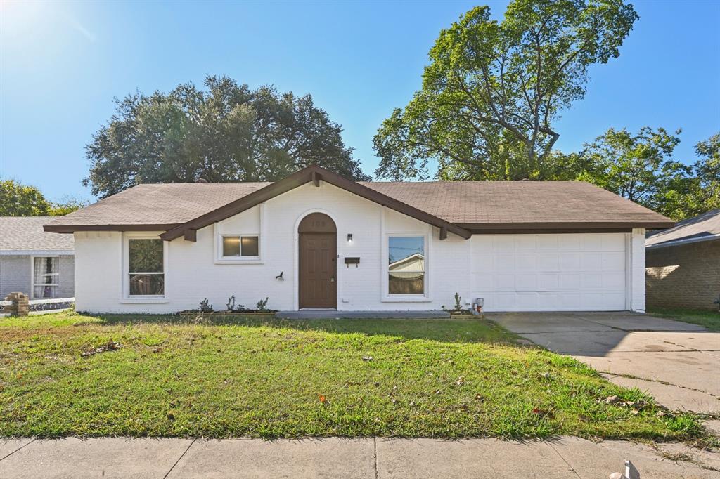 Single story home with a front lawn, brick siding, concrete driveway, and a shingled roof