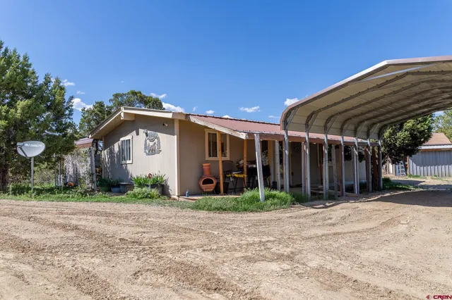 a view of a house next to a yard with road and trees