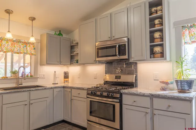 a kitchen with stainless steel appliances granite countertop a sink a stove a microwave and wooden cabinets
