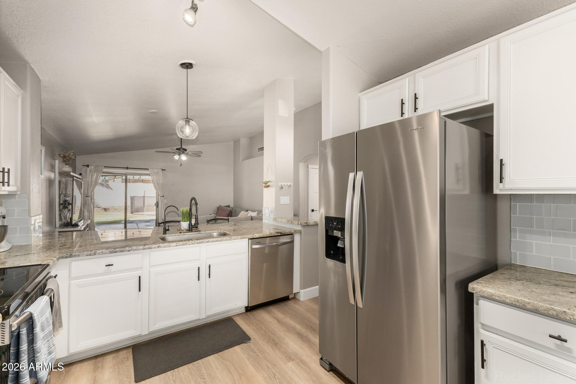 1736 East Robin Lane Gilbert, AZ 85296 - Photo 8 of 25 a kitchen with stainless steel appliances kitchen island granite countertop a refrigerator a sink and white cabinets