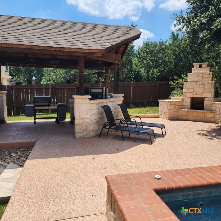11710 Uplands Ridge Drive Austin, TX 78738 - Photo 2 of 33 a view of a patio with a table and chairs under an umbrella with a barbeque