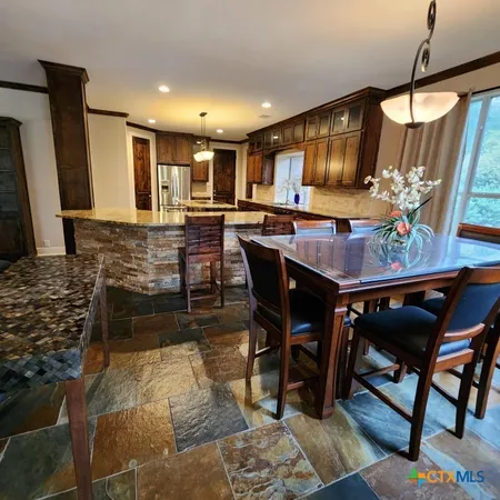 a living room with stainless steel appliances granite countertop furniture a fireplace a rug and a window
