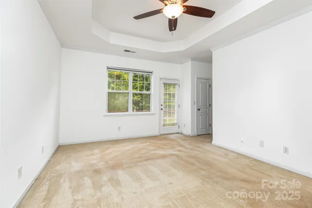 an empty room with a chandelier fan and windows