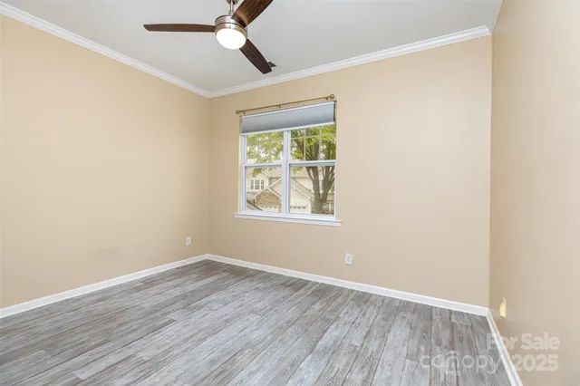 an empty room with wooden floor ceiling fan and windows