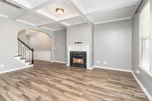a view of an empty room with wooden floor fireplace and a window