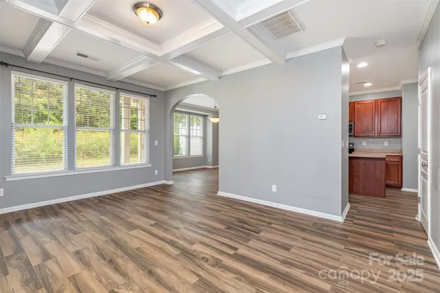 a view of an empty room with window and wooden floor