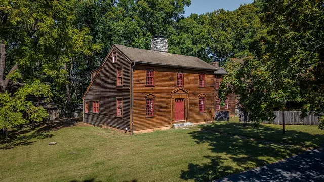 a view of a house with a small yard and large tree