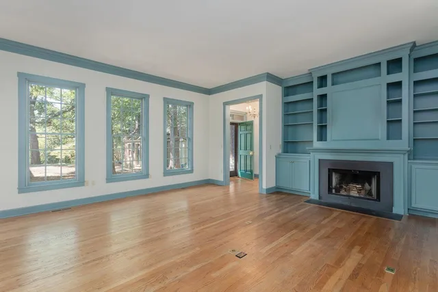a view of an empty room with wooden floor fireplace and a window
