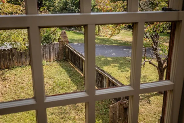 a view of a house with a yard and large trees