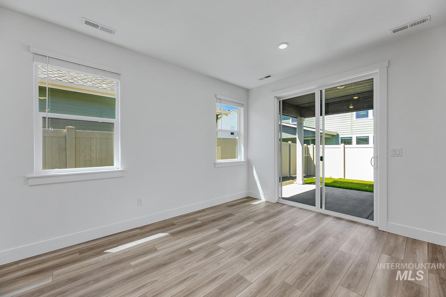 4548 West Wapoot Street Meridian, ID 83646 - Photo 12 of 17 Bright interior space featuring wood-finish flooring, white walls, and a sliding glass door to an outdoor patio