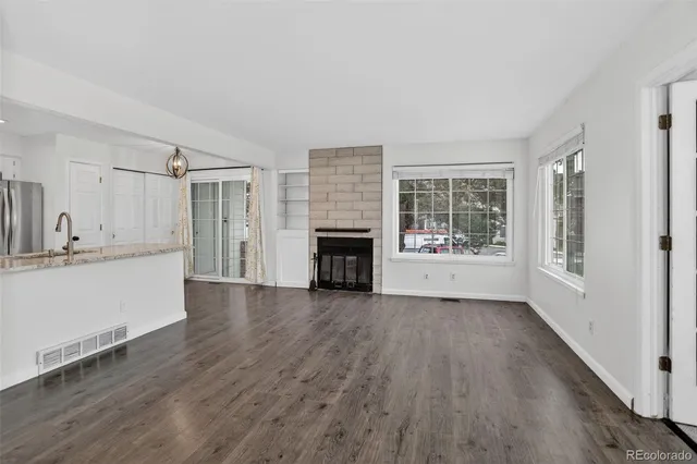 a view of a kitchen and an empty room with wooden floor and a window