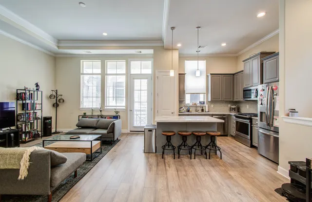 a living room with stainless steel appliances kitchen island granite countertop furniture and a wooden floor