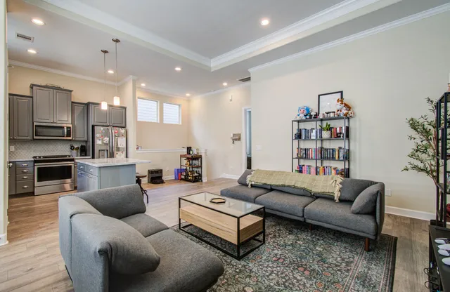 a living room with furniture a flat screen tv and kitchen view
