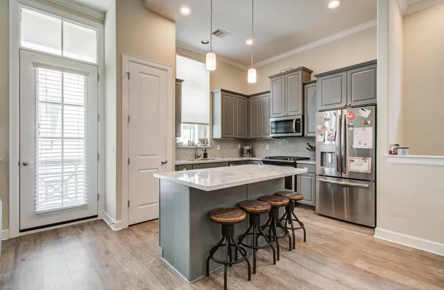 a kitchen with stainless steel appliances granite countertop a refrigerator a sink dishwasher a stove and white countertops with wooden floor