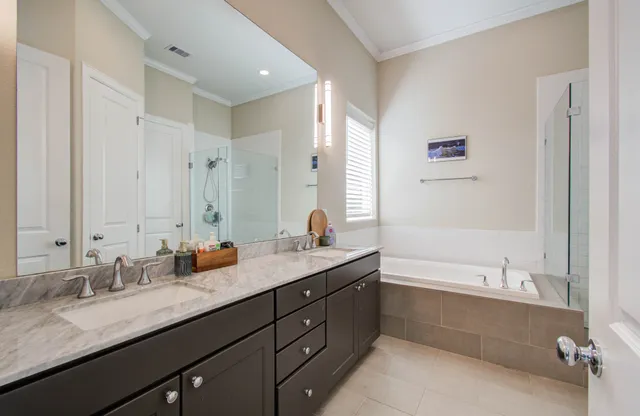 a bathroom with a granite countertop double vanity sink and mirror with bathtub