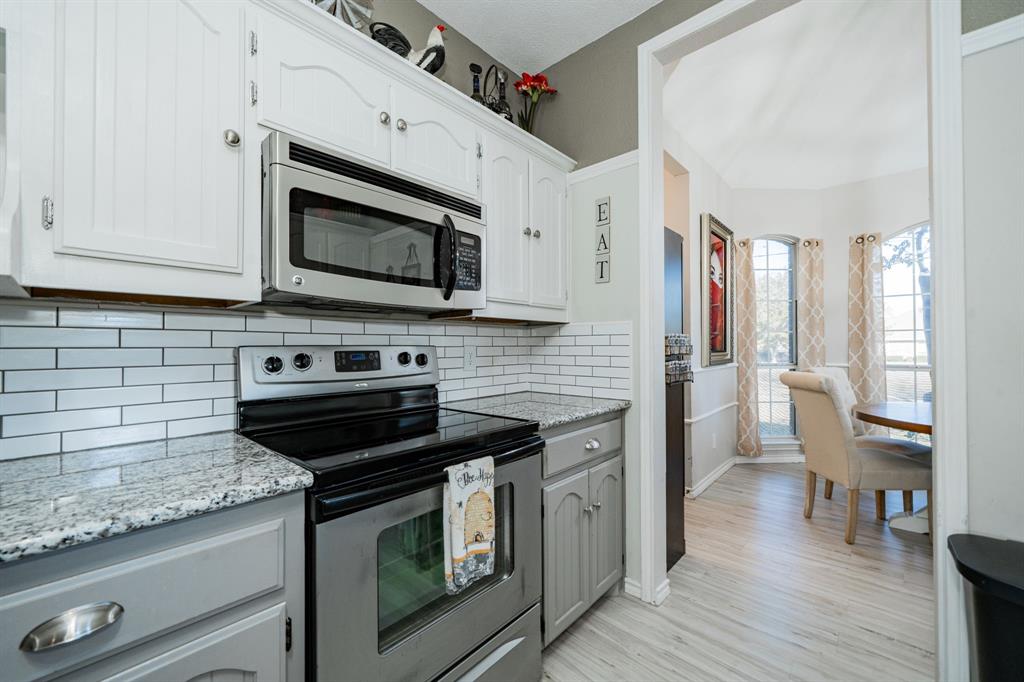 508 Tishomingo Road Waxahachie, TX 75165 - Photo 11 of 26 a kitchen with stainless steel appliances granite countertop a stove and a microwave
