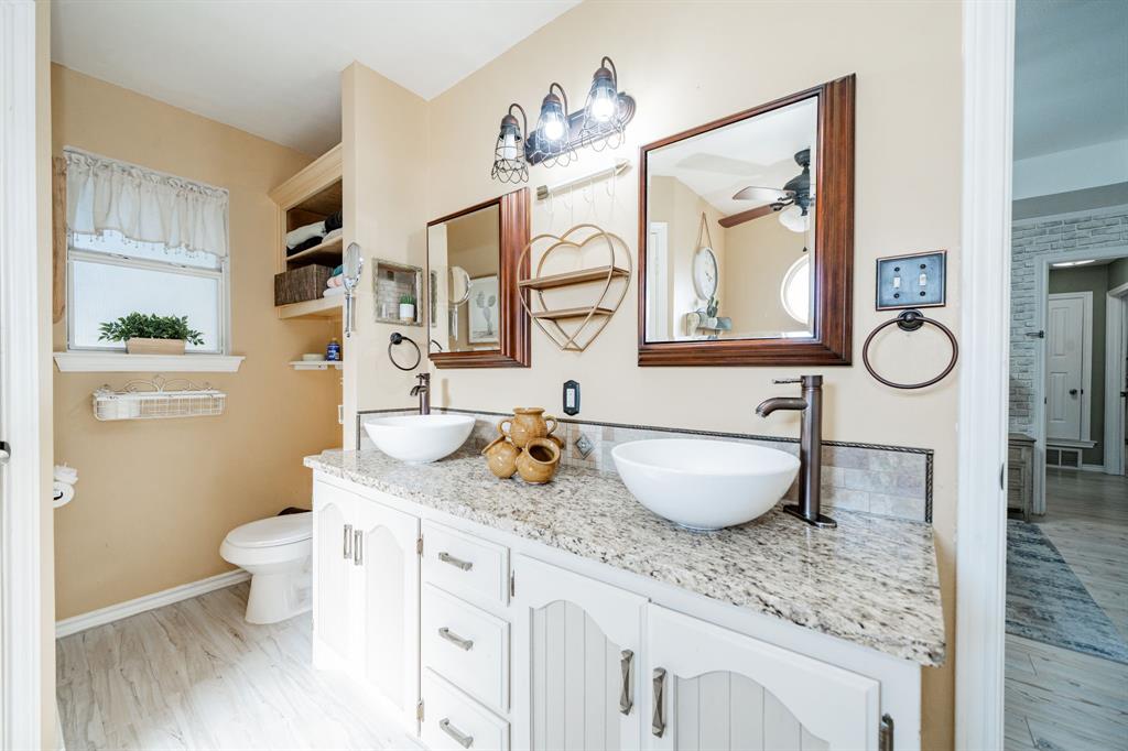 508 Tishomingo Road Waxahachie, TX 75165 - Photo 18 of 26 a bathroom with a granite countertop toilet a sink and a mirror