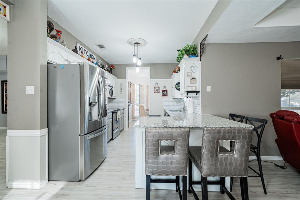 508 Tishomingo Road Waxahachie, TX 75165 - Photo 8 of 26 a kitchen with stainless steel appliances granite countertop a dining table chairs refrigerator and cabinets
