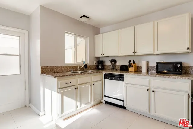 a kitchen with granite countertop white cabinets white appliances and a sink
