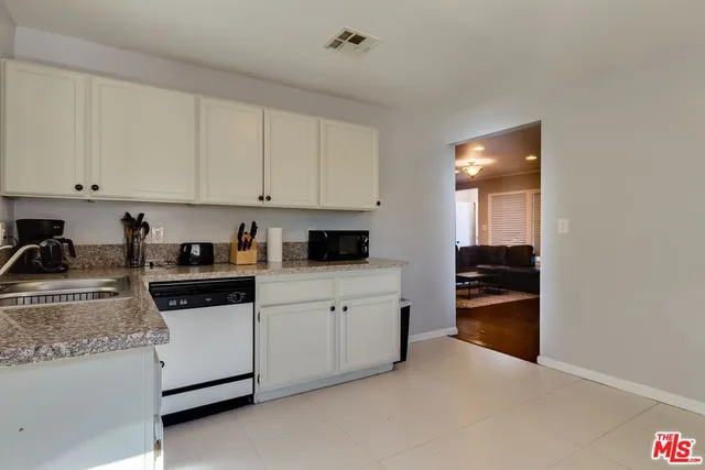 a kitchen with granite countertop white cabinets and stainless steel appliances