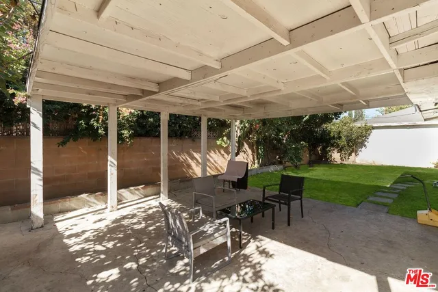 a view of a patio with table and chairs near a yard