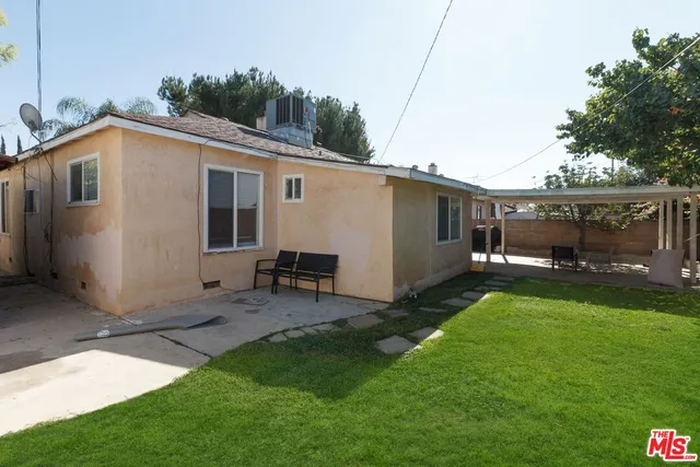 a view of a backyard with couches under an umbrella