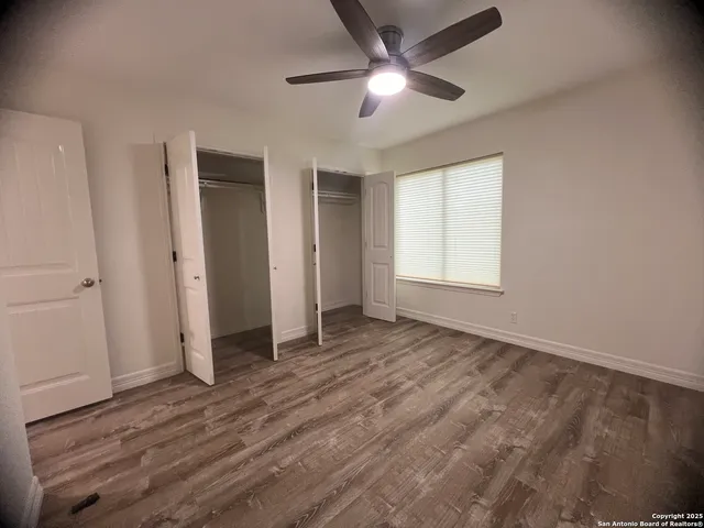an empty room with wooden floor and ceiling fan