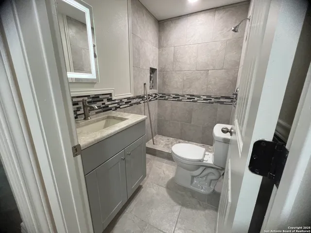 a bathroom with a granite countertop sink toilet and shower