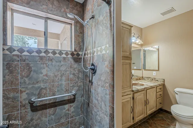 a bathroom with a granite countertop sink a toilet and shower